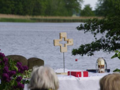 Foto von Altartisch mit Kreuz und Bibel vor einem See